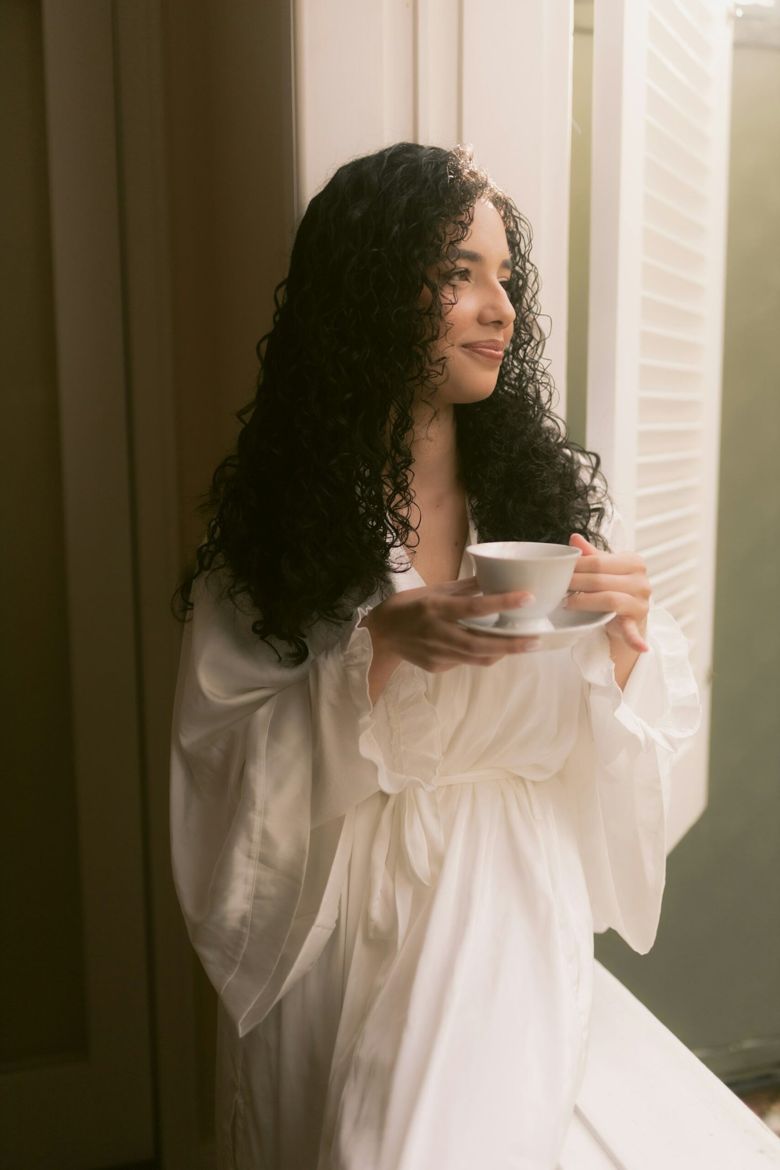Woman holding a warm cup of herbal tea by a softly lit window