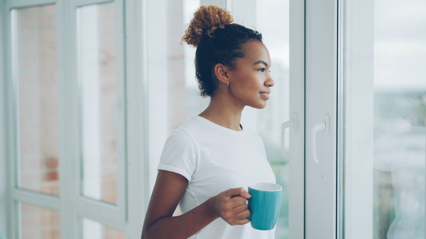 Black woman enjoying a quiet cup of herbal tea beside a window