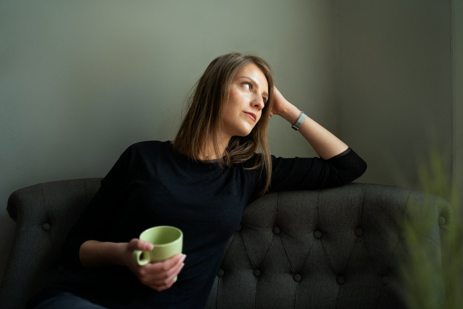 Woman holding a green ceramic mug during a quiet herbal tea pause at home